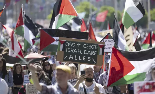 Pro Palestinian protesters demonstrate, during the opening ceremony of the 69th Eurovision Song Contest, in Basel, Switzerland, Sunday, May 11, 2025. Sign read, '11th Commandment: Israel is allowed to do everything.' (Georgios Kefalas/Keystone via AP)