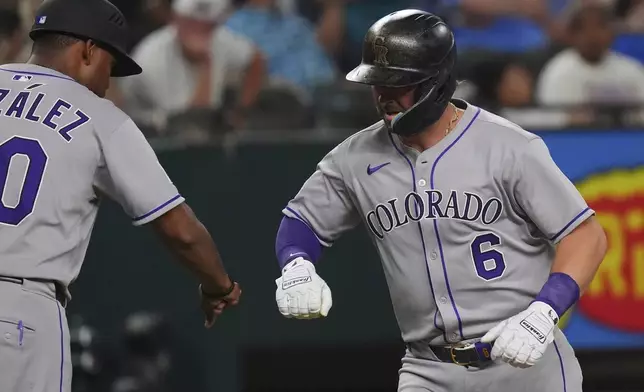 Colorado Rockies' Kyle Farmer (6) celebrates his home run with third base coach Andy González (70) during the sixth inning of a baseball game against the Texas Rangers, Wednesday, May 14, 2025, in Arlington, Texas. (AP Photo/LM Otero)