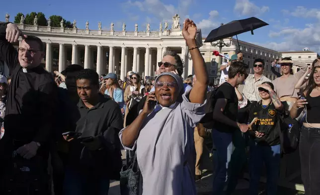 Faithful celebrate after white smoke appeared from the chimney of the Sistine Chapel where 133 cardinals gathered on the second day of the conclave to elect a successor to late Pope Francis, at the Vatican, Thursday, May 8, 2025. (AP Photo/Emilio Morenatti)