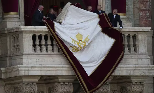 Vatican clerks prepare the central balcony of St Peter's Basilica ahead of the appearance Pope Leo XIV following his election, at the Vatican, Thursday, May 8, 2025. (AP Photo/Luca Bruno)