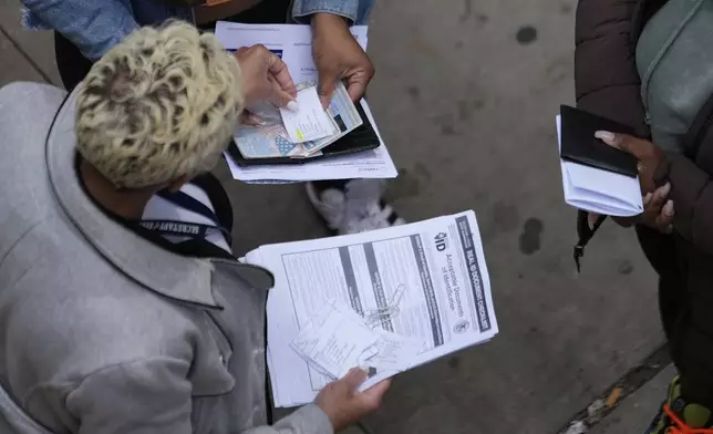 An employee, left, checks on necessary documents as people line up to apply for Real ID at a Real ID Supercenter in downtown Chicago, Tuesday, May 6, 2025. (AP Photo/Kiichiro Sato)