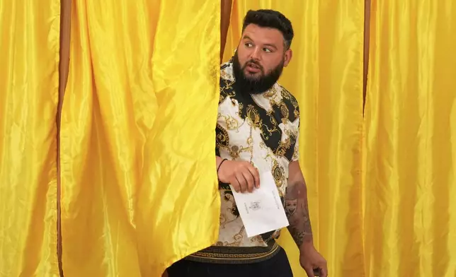 A man exits a voting cabin before casting his vote in the first round of the presidential election redo in Mogosoaia, Romania, Sunday, May 4, 2025. (AP Photo/Vadim Ghirda)