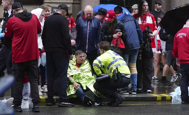 A police officer speaks with a man at the site of an incident on Water Street near the Liver Building in Liverpool after a car collided with pedestrians during the Premier League winners parade, in Liverpool, England, Monday May 26, 2025. (Owen Humphreys/PA via AP)