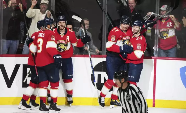 Florida Panthers defenseman Niko Mikkola (77) is congratulated after scoring a goal during the third period in Game 3 of the NHL hockey Stanley Cup Eastern Conference finals against the Carolina Hurricanes Saturday, May 24, 2025, in Sunrise, Fla. (AP Photo/Lynne Sladky)