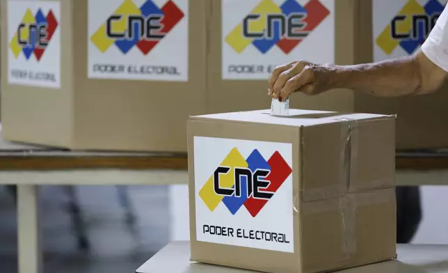 A woman casts a mock vote during a rehearsal for the upcoming regional election, in Caracas, Venezuela, Saturday, May 10, 2025. (AP Photo/Cristian Hernandez)
