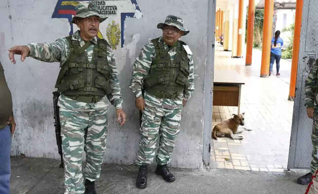 Militia members stand guard at the entrance of a polling station during a rehearsal for the upcoming regional election, in Caracas, Venezuela, Saturday, May 10, 2025. (AP Photo/Cristian Hernandez)