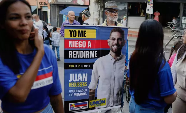 A man holds a banner of Juan Requesens, a candidate for governor of Miranda state in the upcoming regional elections, in Los Teques, Miranda, Venezuela, Thursday, May 15, 2025. (AP Photo/Cristian Hernandez)