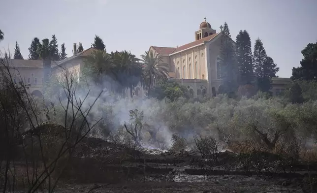 Fire smolders outside of the Roman Catholic Trappist monastery where Israeli fire crew is battling a wild fire in Latrun, Israel, outside of Jerusalem Thursday, May 1, 2025. (AP Photo/Ohad Zwigenberg)