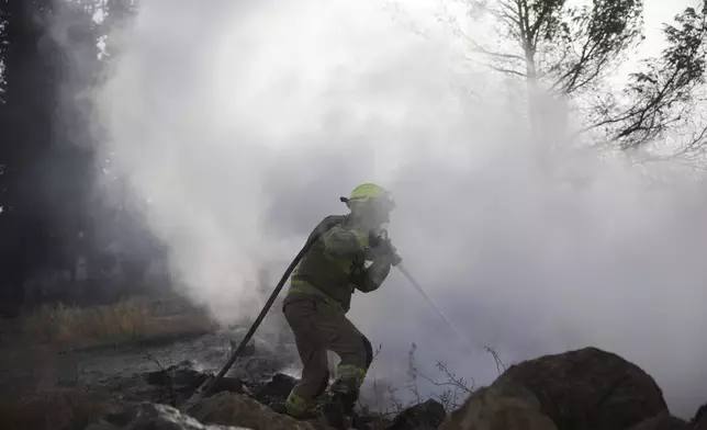 An Israeli firefighter battles a wildfire near Latrun, Israel, outside of Jerusalem, Thursday, May 1, 2025. (AP Photo/Ohad Zwigenberg)