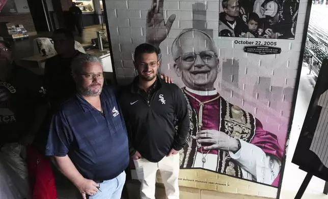 Eddie Schmit III, left, and his son Eddie Schmit IV, right, pose for a photo after a news conference for the Chicago White Sox's commemoration of team fan Pope Leo XIV with a graphic installation at Rate Field before a baseball game between the Seattle Mariners and the White Sox in Chicago, Monday, May 19, 2025. (AP Photo/Nam Y. Huh)