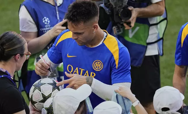Inter Milan's Lautaro Martinez signs autographs at the end of a training session ahead of the Champions League final soccer match between Paris Saint-Germain and Inter Milan in Munich, Germany, Friday, May 30, 2025. (AP Photo/Martin Meissner)