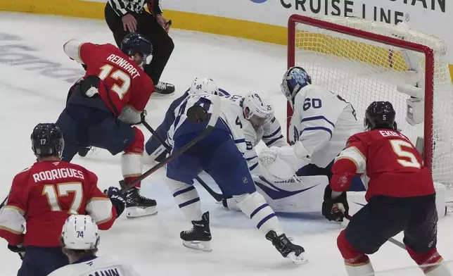 Toronto Maple Leafs defenseman Brandon Carlo (25) and goaltender Joseph Woll (60) attempt to stop a shot on goal by Florida Panthers center Sam Reinhart (13) during the second period in Game 3 of a second-round NHL hockey playoff series, Friday, May 9, 2025, in Sunrise, Fla. Officials ruled the puck crossed the goal line. (AP Photo/Marta Lavandier)