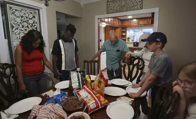 Haitian immigrants Sherlie Jean, left, holds hands with her husband Kevenson Jean during a prayer before eating with friends, Monday, April 14, 2025, in Panhandle, Texas. (AP Photo/Eric Gay)