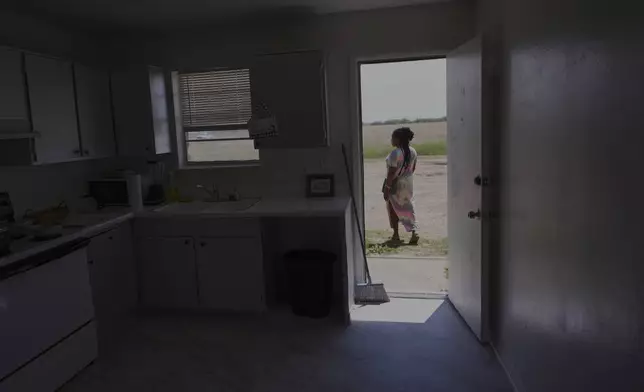 Nicole, a Haitian immigrant who works for a meat processing plant, looks for wild flowers outside her apartment, Sunday, April 13, 2025, in Dumas, Texas. (AP Photo/Eric Gay)