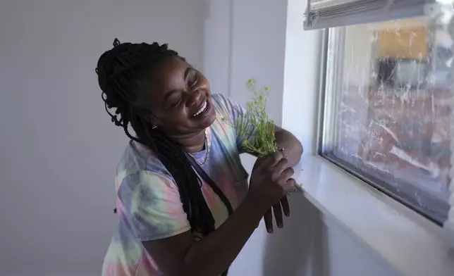 Nicole, a Haitian immigrant who works for a meat processing plant, holds wild flowers she picked near her apartment, Sunday, April 13, 2025, in Dumas, Texas. (AP Photo/Eric Gay)