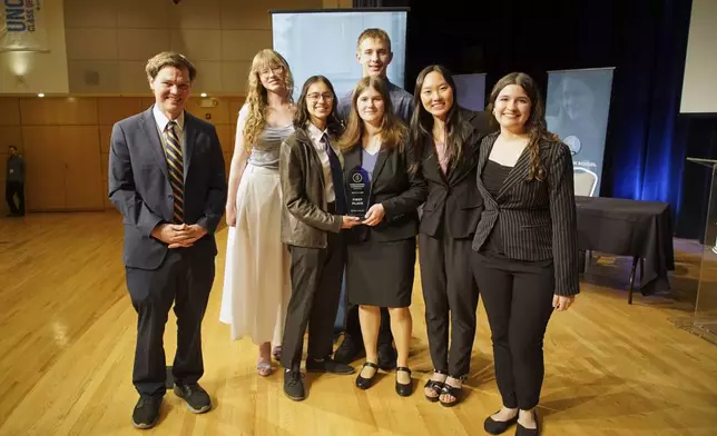 From left, students Luke Calhoun, Olivia Beazer, Sona Zarkou, Mae Bradford, front, Lincoln Bradford, back, Cindy Huang and Juliana Migliati from Arizona's BASIS Flagstaff Charter School pose with the first place trophy after winning the National High School Ethics Bowl in Chapel Hill, N.C., on Sunday, April 13, 2025. (AP Photo/Allen G. Breed)