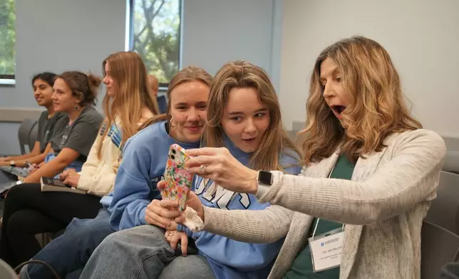 From right, coach Amy Miller, Larkin Wilson, Sadie Osenga, Thalia Vidalakis, Katherine Thomas and Ashley Maliakal from The Harpeth Hall School in Nashville, Tenn., take a selfie during a match at the National High School Ethics Bowl in Chapel Hill, N.C., on Sunday, April 13, 2025. (AP Photo/Allen G. Breed)
