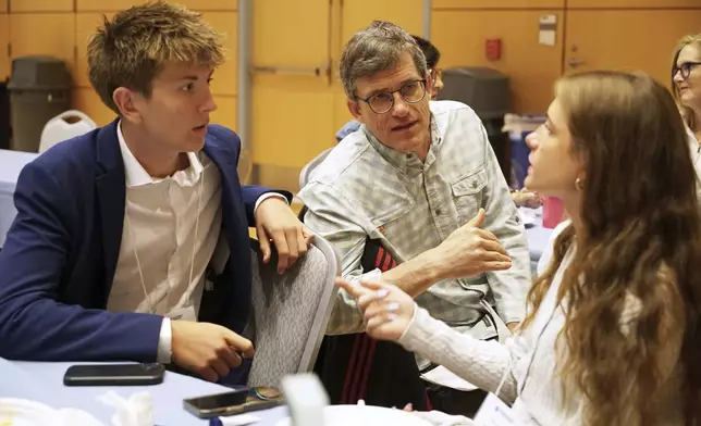 Midtown High School Ethics Bowl teammates Eric Snell, left, and Eve Nahmias speak with coach Eddy Nahmias, Eve's father, in between rounds of the National High School Ethics Bowl in Chapel Hill, N.C., on Sunday, April 13, 2025. (AP Photo/Allen G. Breed)