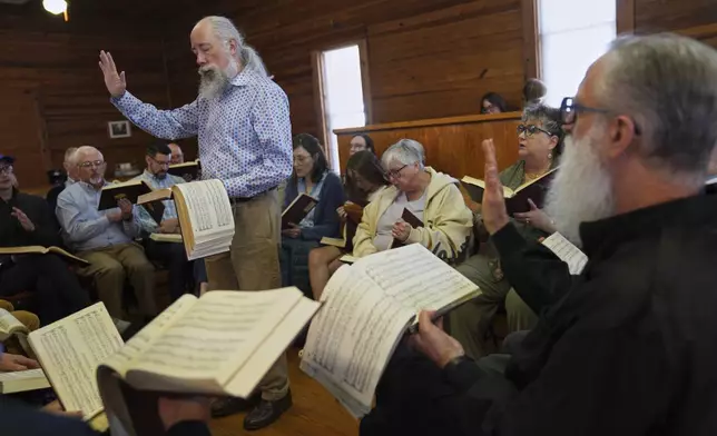 Andy Ditzler stands in the center of a hollow square, "The Sacred Harp" formation in which singers organize into four voice parts and face each other to create an opening in the middle, at Holly Springs Primitive Baptist Church in Bremen, Ga., on Saturday, March 22, 2025. (AP Photo/Jessie Wardarski)