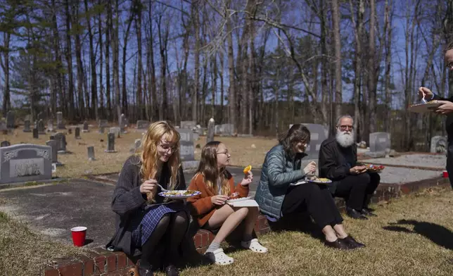 Sacred Harp singers sit among the headstones at Holly Springs Primitive Baptist Church for a midday potluck in Bremen, Ga., on Saturday, March 22, 2025. (AP Photo/Jessie Wardarski)