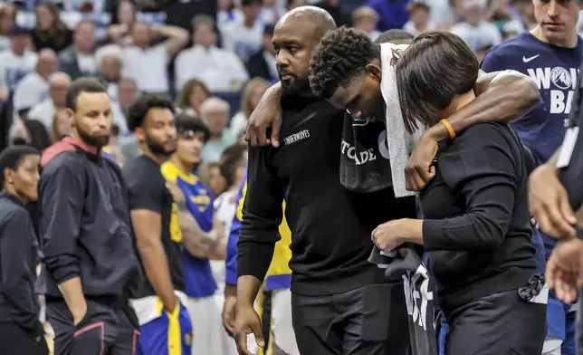 Minnesota Timberwolves guard Anthony Edwards (5) is helped off the court after sustaining an injury during the first half of Game 2 of an NBA basketball second-round playoff series against the Golden State Warriors, Thursday, May 8, 2025, in Minneapolis. (Carlos Avila Gonzalez/San Francisco Chronicle via AP)