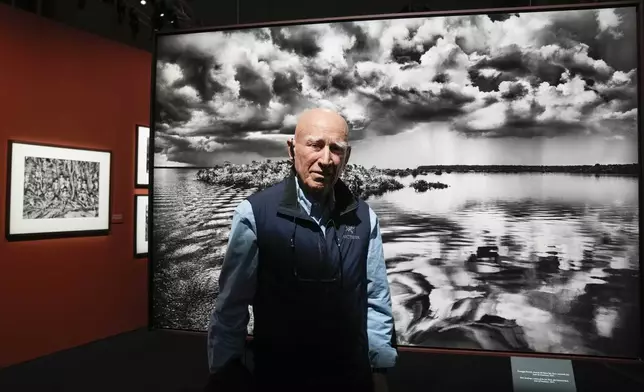 FILE - Brazilian photographer Sebastiao Salgado, poses in front of one of the pictures of his exhibition 'Amazonia', at the Fabbrica del Vapore, in Milan, Italy, Thursday, May 11, 2023. (AP Photo/Luca Bruno, file)