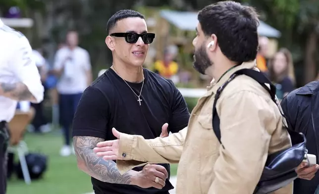 Puerto Rican singer Daddy Yankee, left, speaks with an acquaintance in the paddock area ahead of the Formula One Miami Grand Prix auto race, Thursday, May 1, 2025, in Miami Gardens, Fla. (AP Photo/Rebecca Blackwell)