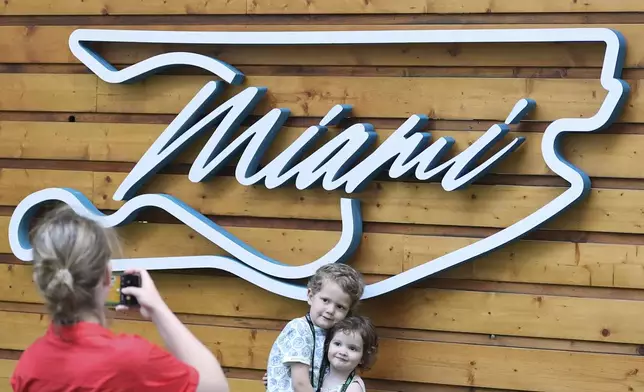 Aaron Mart, 4, and his sister Eloise, 2, whose father is an engineer for the Red Bull team, have their photo taken by their mother Anne Bachelay in front of a Formula One Miami Grand Prix auto race logo in the shape of the track, Thursday, May 1, 2025, in Miami Gardens, Fla. (AP Photo/Rebecca Blackwell)