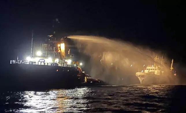 A firefighting-equipped tug boat, left, contacted by the Malta Vessel Traffic Services (VTS) helps controlling a fire occurred on the bow of the Conscience vessel in international waters of the Mediterranean Sea, Friday, May 2, 2025. (Malta Vessel Traffic Services via AP)
