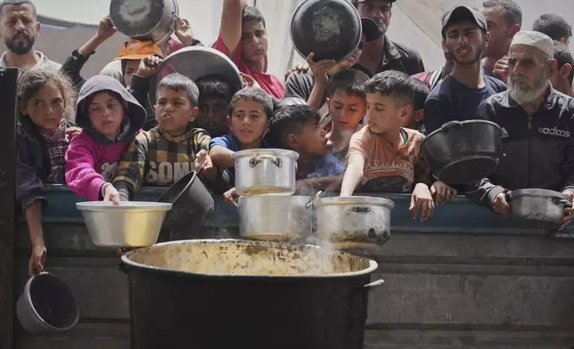 Palestinians wait to get food at a community kitchen in Khan Younis, in southern Gaza Strip, Thursday April 24, 2025.(AP Photo/Abdel Kareem Hana)