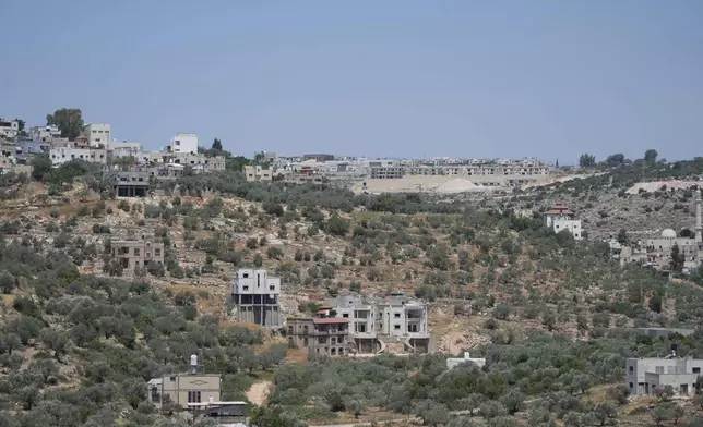 A general view shows the Israeli settlement of Bruchin, center on top of a hill and adjacent to the West Bank village of Bruqin, that was under attack by Israeli settlers overnight and left several burnt vehicles and damaged homes, residents said, near Salfit, Friday, May 23, 2025. (AP Photo/Nasser Nasser)