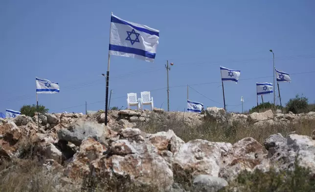 Israeli flags fly flutter on top of a hill that is adjacent to Palestinian properties that were under attack by Israeli settlers overnight, leaving several burnt vehicles and damaged homes, residents said, in the West Bank village of Bruqin, near Salfit, Friday, May 23, 2025. (AP Photo/Nasser Nasser)