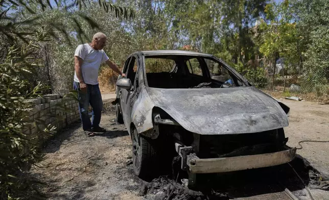 Palestinian landlord Akram Sabra, 60, stands next to a vehicle burnt under attack by Israeli settlers overnight, in the West Bank village of Bruqin, near Salfit Friday, May 23, 2025. (AP Photo/Nasser Nasser)