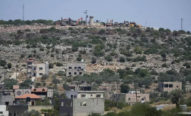 Bulldozers work by an Israeli settlers outpost, near the Israeli settlement of Bruchin, on top of a hill and overlooking the adjacent West Bank village of Bruqin, that was under attack by Israeli settlers overnight and left several burnt vehicles and damaged homes, residents said, near Salfit, Friday, May 23, 2025. (AP Photo/Nasser Nasser)