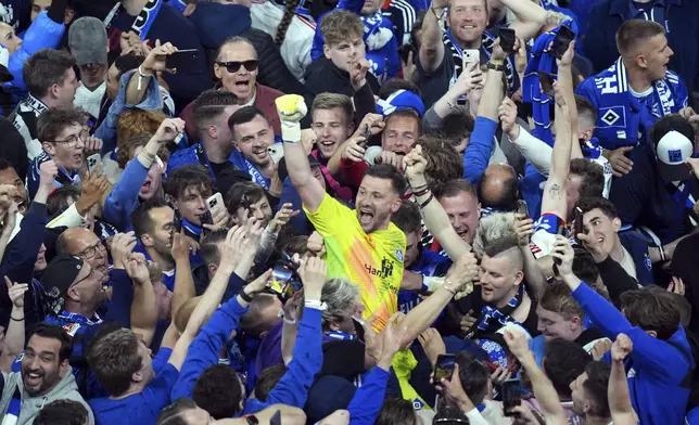 Hamburg goalkeeper Daniel Heuer Fernandes celebrates with fans who stormed the pitch to celebrate promotion following a Bundesliga 2 soccer game between Hamburger SV and SSV Ulm 1846 in Hamburg, Germany, Saturday, May 10, 2025. (Marcus Brandt/dpa via AP)