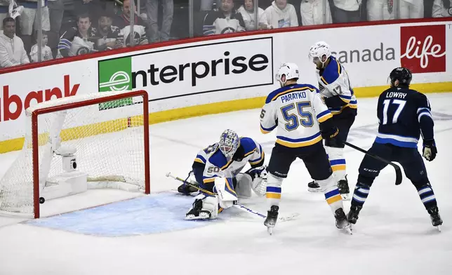 Winnipeg Jets' Adam Lowry (17) scores the game-winning goal against the St. Louis Blues' goaltender Jordan Binnington (50) in the second overtime period of Game 7 in an NHL hockey first-round playoff series in Winnipeg, Manitoba, Sunday, May 4, 2025. (Fred Greenslade/The Canadian Press via AP)