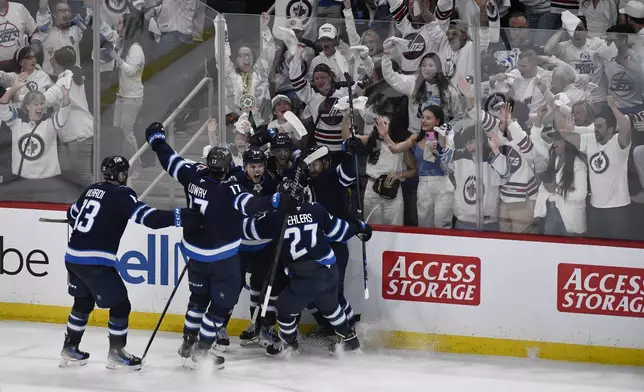 Winnipeg Jets' Cole Perfetti (91) celebrates after his goal with teammates to tie the St. Louis Blues during during the third period of Game 7 in an NHL hockey first-round playoff series in Winnipeg, Manitoba, Sunday, May 4, 2025. (Fred Greenslade/The Canadian Press via AP)