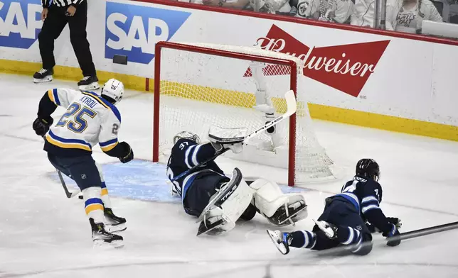 St. Louis Blues' Jordan Kyrou (25) scores against Winnipeg Jets' goaltender Connor Hellebuyck (37) during the first period of Game 7 in an NHL hockey first-round playoff series in Winnipeg, Manitoba, Sunday, May 4, 2025. (Fred Greenslade/The Canadian Press via AP)