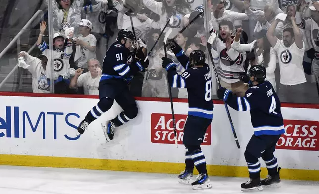 Winnipeg Jets' Cole Perfetti (91) celebrates after his goal to tie the St. Louis Blues with Kyle Connor (81) and Neal Pionk (4) during the third period of Game 7 in an NHL hockey first-round playoff series in Winnipeg, Manitoba, Sunday, May 4, 2025. (Fred Greenslade/The Canadian Press via AP)