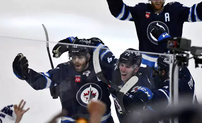 Winnipeg Jets' Adam Lowry (17) celebrates his game-winning goal against the St. Louis Blues with Haydn Fleury (24) in the second overtime period of Game 7 in an NHL hockey first-round playoff series in Winnipeg, Manitoba, Sunday, May 4, 2025. (Fred Greenslade/The Canadian Press via AP)