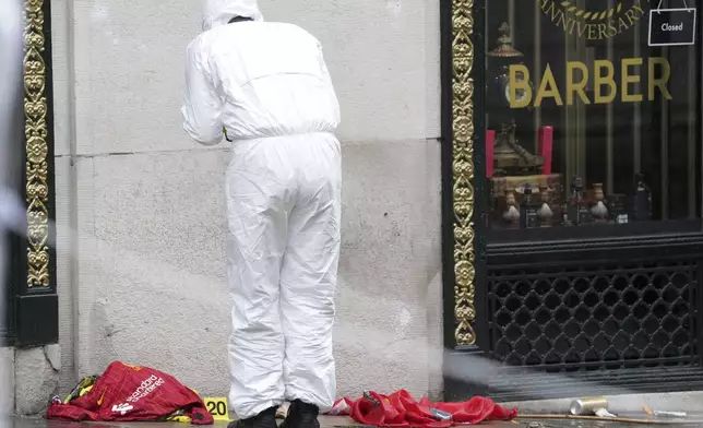 A Forensic officer looks at evidence near the site where a 53-year-old British man plowed a minivan into a crowd of Liverpool soccer fans who were celebrating the city's Premier League championship Monday, injuring more than 45 people in Liverpool, England, Tuesday, May 27, 2025.(AP Photo/Jon Super)