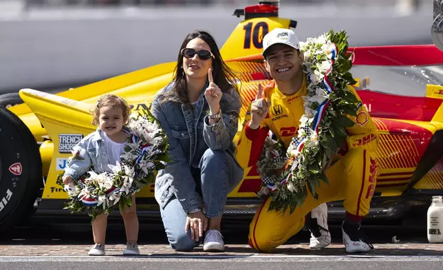 Indianapolis 500 champion Alex Palou, of Spain, poses with his wife Esther Valle, center, and daughter Lucia during the traditional winners photo session at Indianapolis Motor Speedway in Indianapolis, Monday, May 26, 2025. (AP Photo/Michael Conroy)