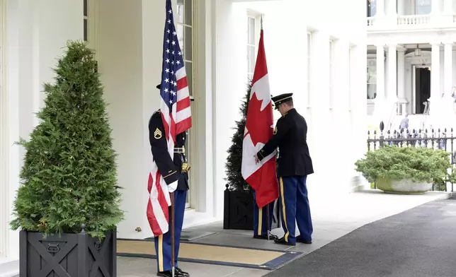 A member of the military detail adjusts the Canadian flag prior to the arrival of Prime Minister Mark Carney for a meeting with U.S. President Donald Trump, at the White House in Washington, D.C., Tuesday, May 6, 2025. (Adrian Wyld /The Canadian Press via AP)