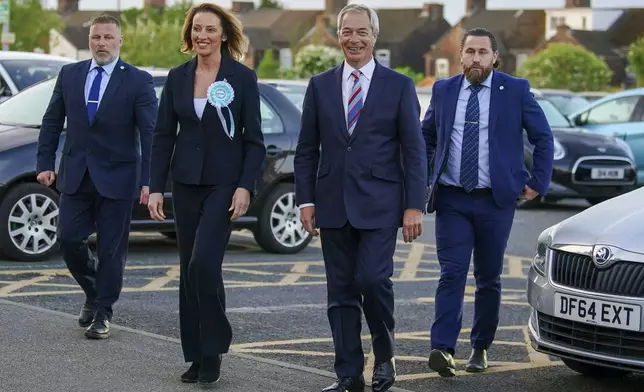 Reform UK candidate Sarah Pochin, second left and party leader Nigel Farage, second right, arrive at the DCBL Halton Stadium ahead of the result of the Runcorn and Helsby by-election at DCBL Halton Stadium, Widnes, Cheshire, Friday, May 2, 2025. (Peter Byrne/PA via AP)