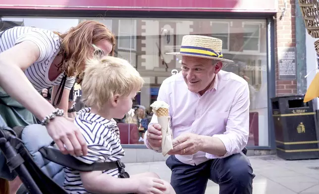Liberal Democrat Leader Sir Ed Davey serves up ice cream in the hot weather in Shrewsbury, Shropshire, England, to thank voters following the local elections, on Friday May 2, 2025. (James Street/PA via AP)