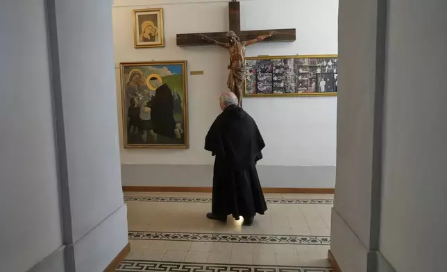 Augustinian friar Paolo Angelone walks by a crucifix in the Sanctuary of Our Mother of Good Counsel during an interview in Genazzano, Italy, Thursday, May 15, 2025. (AP Photo/Gregorio Borgia)