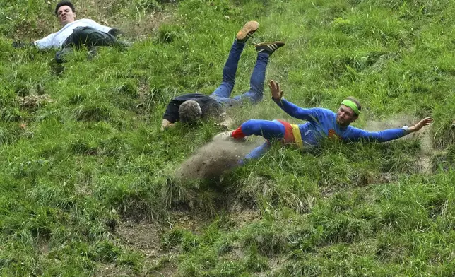 Participants compete in the men's downhill race category of the traditional annual Cheese Rolling contest at Cooper's Hill in Brockworth, Gloucestershire, England, Monday, May 26, 2025.(AP Photo/Anthony Upton)