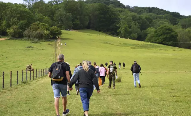 Spectators walk up Cooper's Hill to watch the traditional annual Cheese Rolling contest at in Brockworth, Gloucestershire, England, Monday, May 26, 2025.(AP Photo/Anthony Upton)