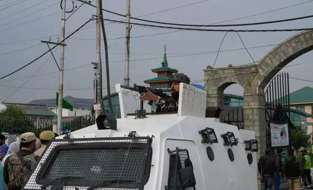 An Indian soldier and policemen guard as the first batch of Kashmiri Muslim pilgrims, departs for the annual pilgrimage to Mecca, Islam's holiest site, in Srinagar, Indian-controlled Kashmir, Sunday, May 4, 2025. (AP Photo/Mukhtar Khan)
