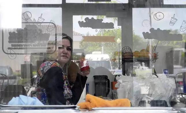 Manager Yrene Bruno is seen through reflective glass as she sits inside a franchise of "Sabor Venezolano," one of 18 businesses owned by Wilmer Escaray which employ scores of Venezuelan immigrants with Temporary Protected Status (TPS) who are now potentially exposed to deportation, in Doral, Fla., Tuesday, May 20, 2025. (AP Photo/Rebecca Blackwell) (AP Photo/Rebecca Blackwell)